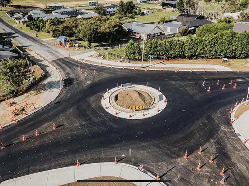 A roundabout with construction cones and trees